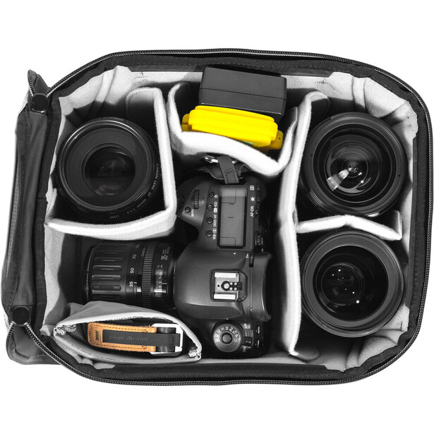 Professional camera gear organized in a protective case with dual lenses, body, accessories, and yellow battery pack.