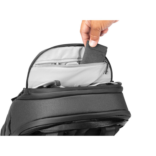 Hand removing a gray padded divider from the top compartment of a camera bag.