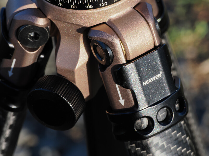 Close-up of a camera tripod head with panoramic scale and mounting plate in natural daylight.