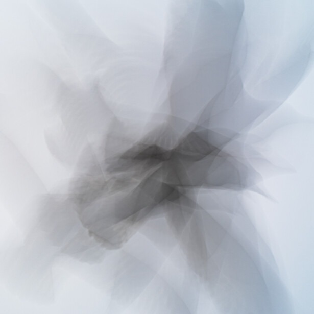 Abstract motion blur photograph with layered angular shapes radiating from center.