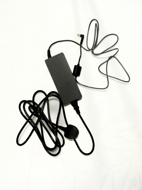 Compact AC power adapter with coiled cable and connector plugs on white background.