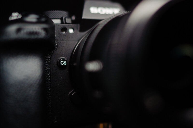 Sony C8 mirrorless camera body with attached lens in dramatic side-lit studio lighting.