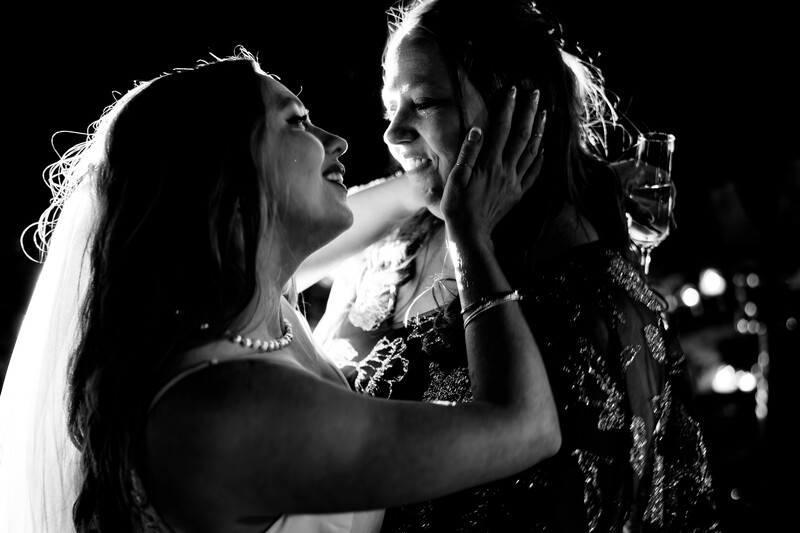 Two women embracing face-to-face in dramatic black and white lighting.