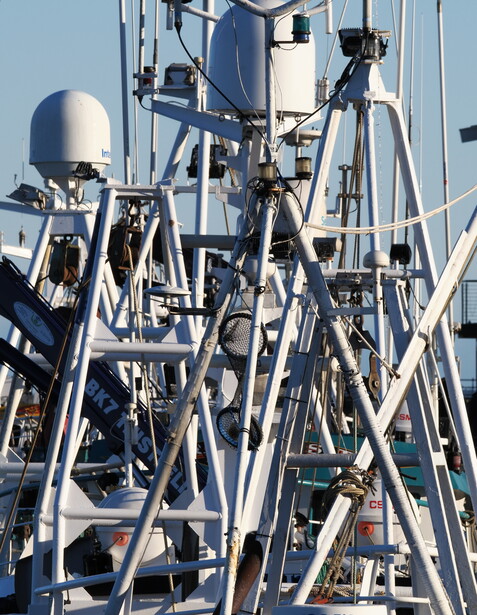 Complex array of satellite dishes and communication antennas mounted on a metal tower structure against blue sky.
