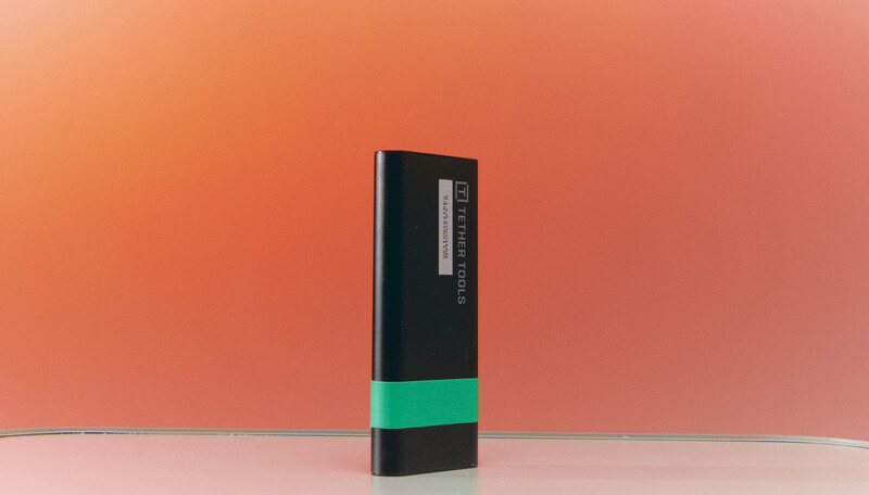 Rectangular product with black top section, green middle band, and dark base on gradient peach background.