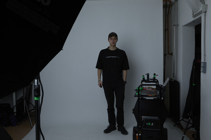Man standing in front of a white cyclorama background during a professional portrait photography session.
