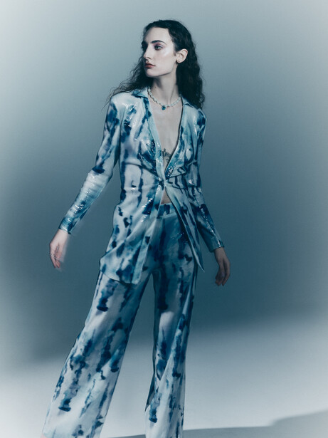 Woman in blue tie-dye wrap dress standing against neutral background.