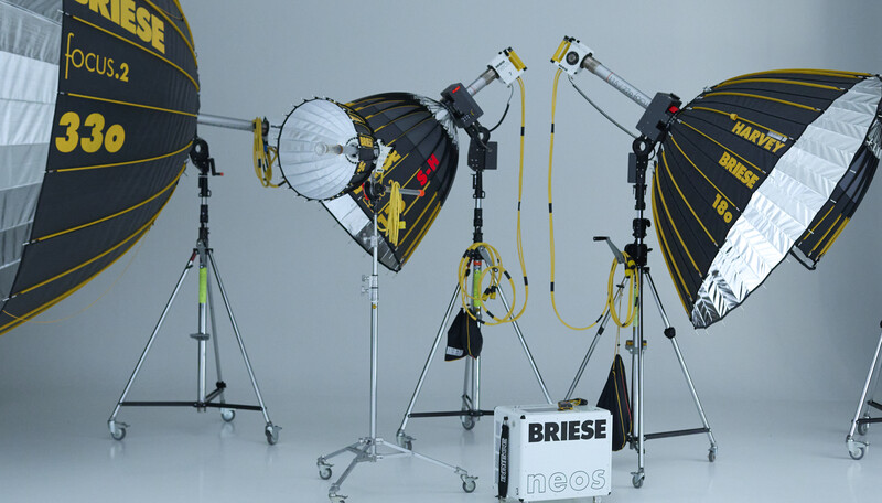 Professional film production lighting kit with parabolic reflectors, stands, and mounting hardware arranged on white backdrop.