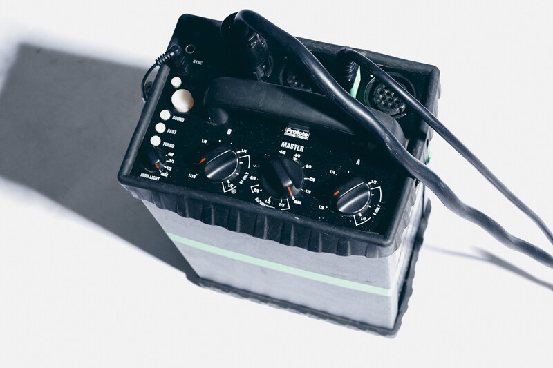 Vintage light meter with analog dials and controls on white background with shadow.