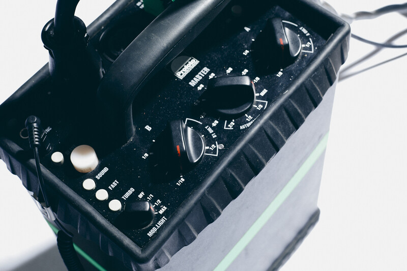 Close-up of a black digital multimeter with rotary dial and control buttons on a light background.