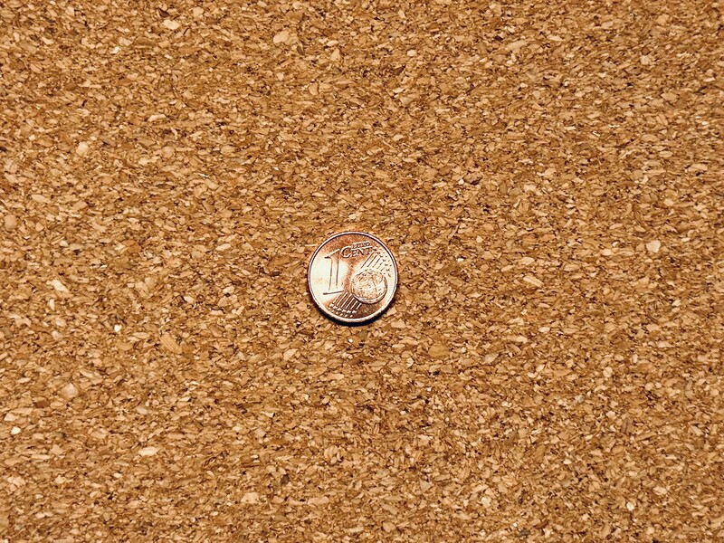 One-cent penny centered on a cork surface with natural lighting and shadow detail.