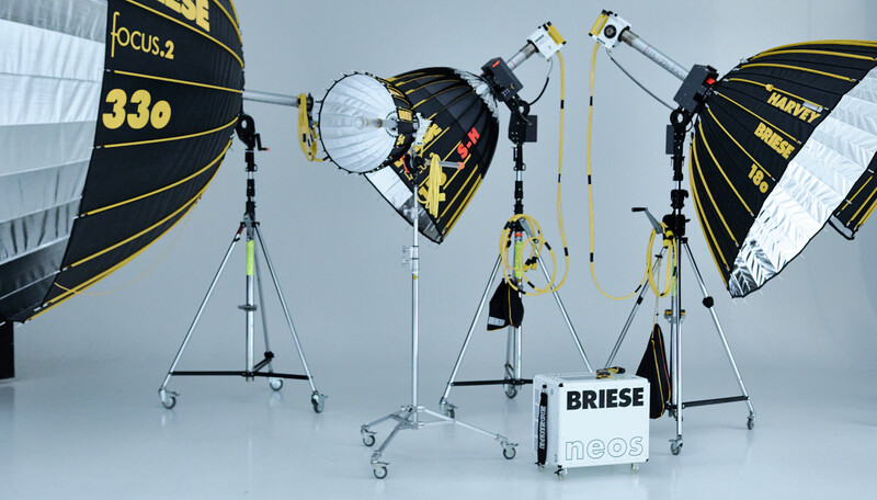 Professional film and television lighting equipment including large parabolic reflectors and fresnel lights mounted on wheeled stands.