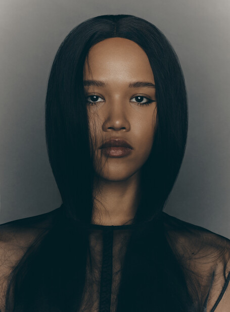 Portrait of a woman with long black hair against a neutral gray background.