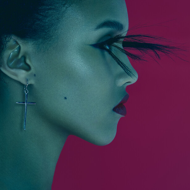 Profile of a woman with dramatic eye makeup and feathered false lashes against a split teal and magenta background.