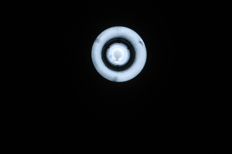Ring light with frosted diffuser and central reflective element against black background.