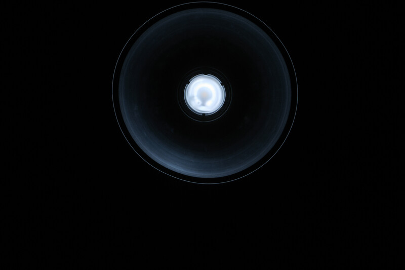 Close-up view of a flashlight beam creating a bright circular spot against a dark background.