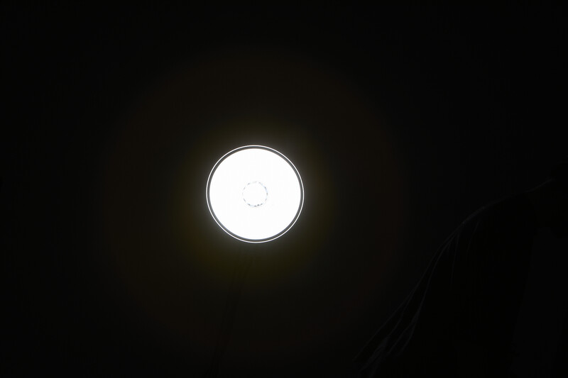 Bright circular light source glowing against a dark background with subtle vignetting.