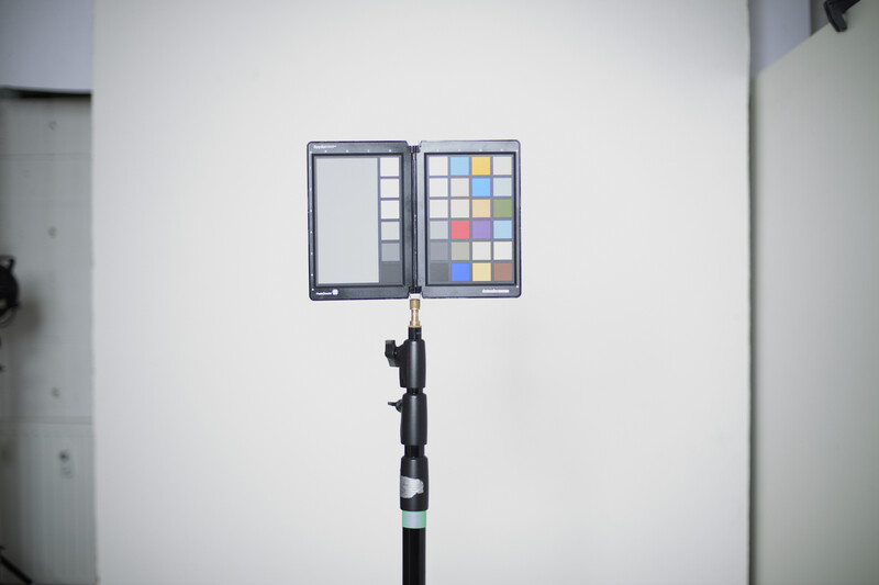 Color reference chart mounted on a black pole against a white wall.