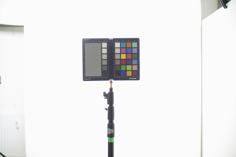 Color checker chart mounted on a black pole against a white backdrop.