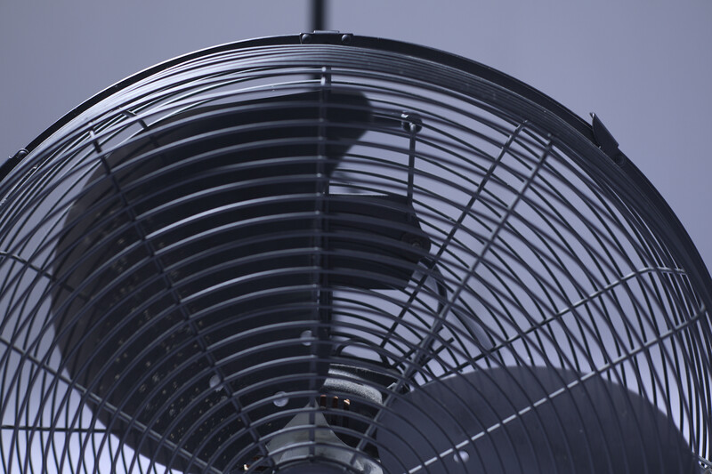 Close-up view of a large industrial fan's metal grille and blades against a gray sky.