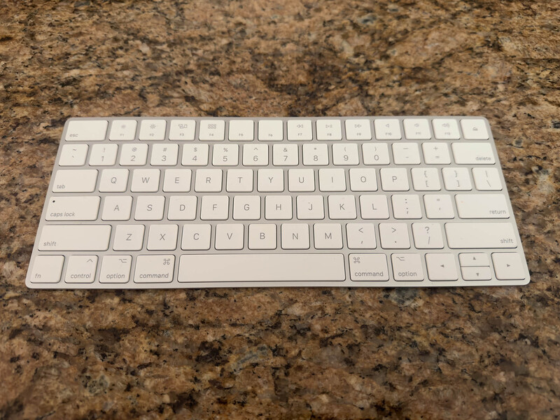 White wireless keyboard on a granite countertop surface.