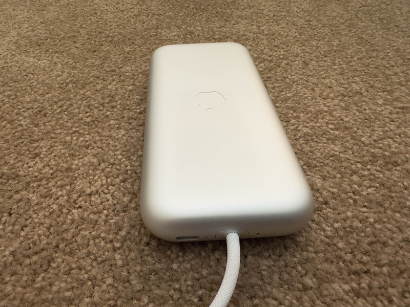 White portable battery pack with charging cable on carpet surface.