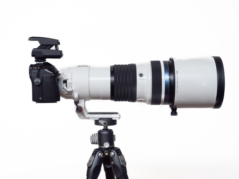 Telephoto lens mounted on camera body and tripod with ball head.
