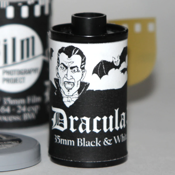 Vintage film canister with Dracula graphics and black-and-white design on neutral background.