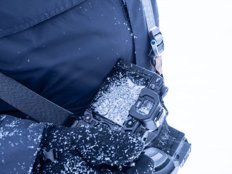 Heavy snow accumulation on a digital sports watch and winter glove during outdoor cold weather conditions.