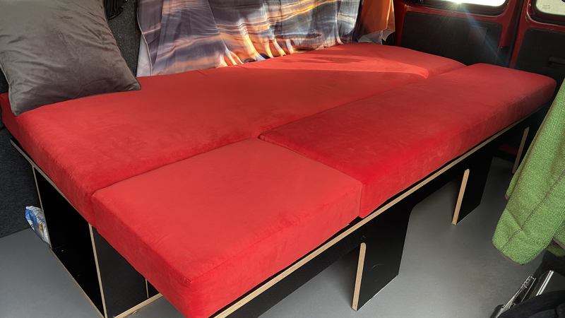 Red upholstered modular sofa with wooden legs displayed in a showroom setting.