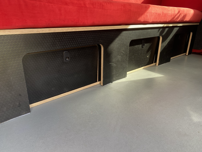 Interior architectural detail showing black perforated acoustic panels with wood trim beneath a red ceiling element.