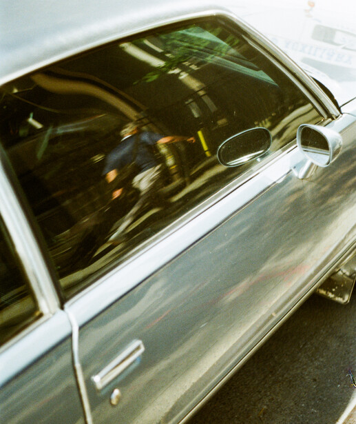 Top-down view of a classic car's open window with tinted glass and chrome trim against white body paint.
