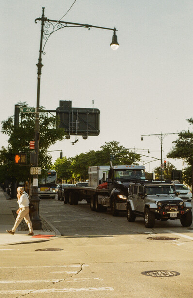 Pedestrian crossing a street at an intersection with vintage trucks and street lamp.
