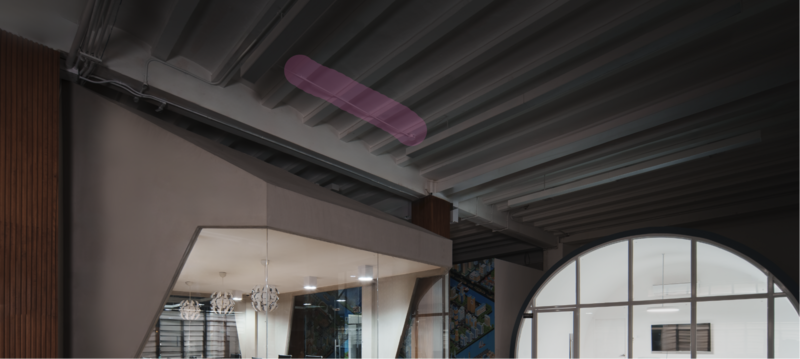 Industrial loft interior with exposed ceiling beams, modern mezzanine, and large arched window.