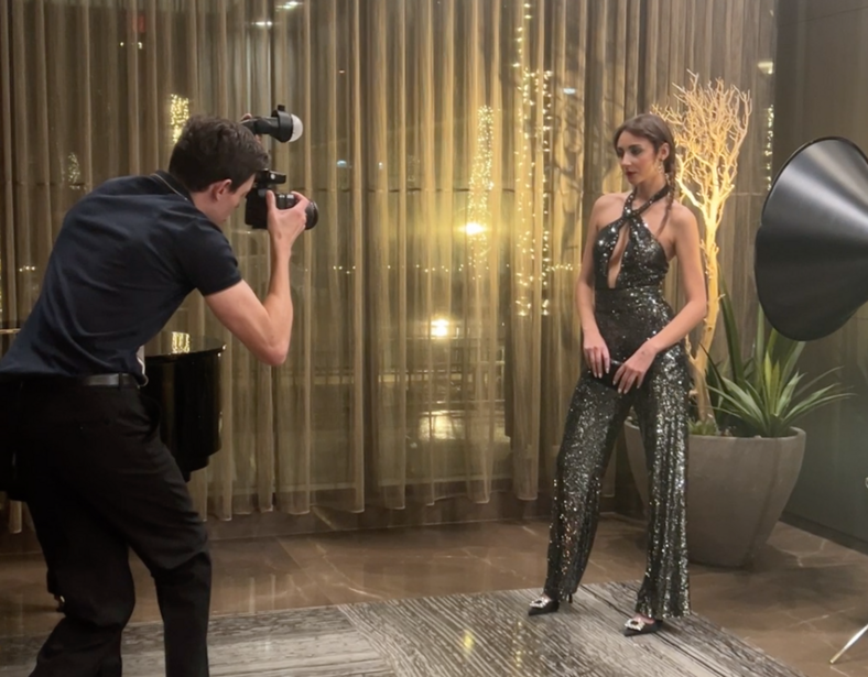 Photographer shooting a portrait of a woman in a sequined dress against an illuminated backdrop.