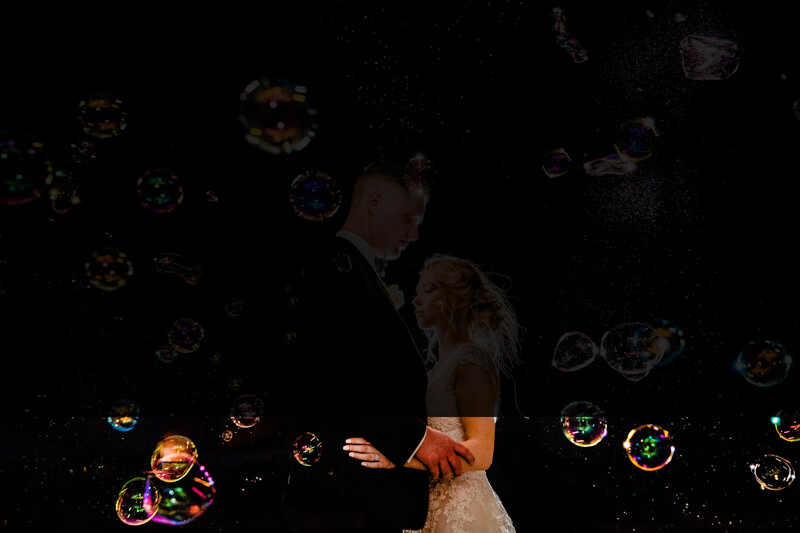 Couple surrounded by illuminated bubbles against a dark background during an intimate moment.