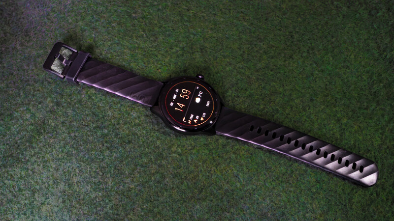 Black digital smartwatch with rectangular face displaying time and data on green textured background.