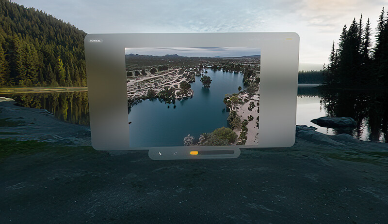 Drone footage of a lakeside community displayed on a tablet screen positioned in a forest landscape.