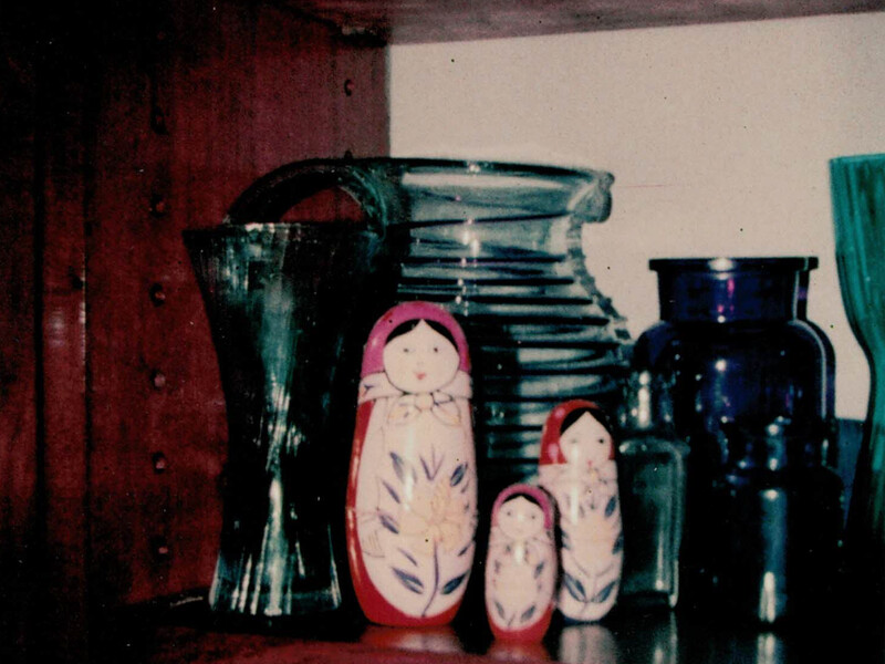 Russian nesting dolls and vintage glass vessels arranged in a still life composition.