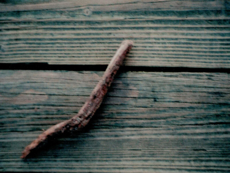 Weathered wooden stick curved diagonally across blue-green painted wooden boards.