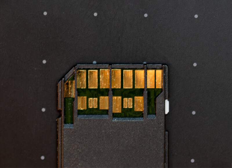 Aerial view of a residential street with parked cars and lit windows at dusk or night.