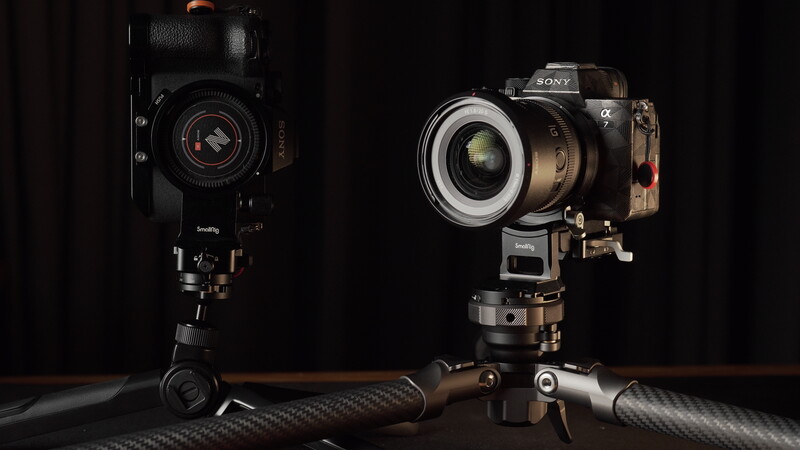 Two cinema cameras mounted on a carbon fiber rod rig, lit against a black background.