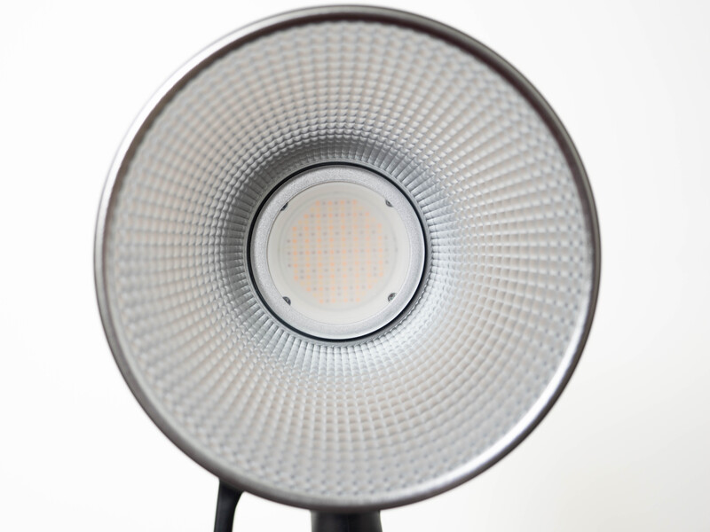 Ring light with diffuser dome and central LED module mounted on stand against white background.
