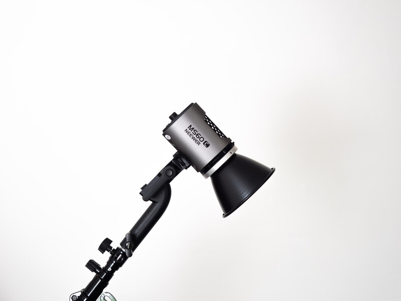 Black studio flash head mounted on a boom arm against a white background.