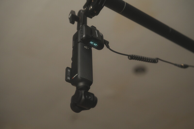 Wireless lavalier microphone mounted on a boom arm with coiled cable attached.