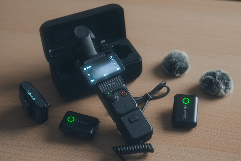 DJI Osmo gimbal controller with wireless microphones and accessories laid out on a wooden surface.