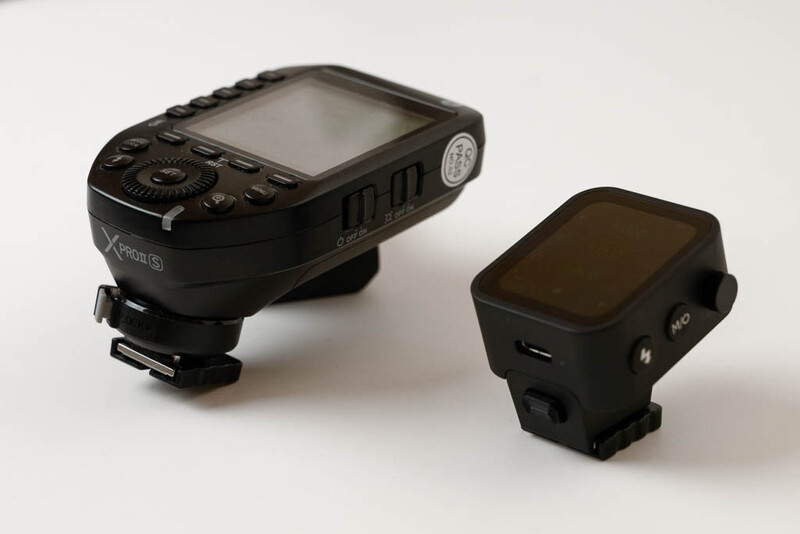 Two black camera flash transmitters displayed side by side on white background.