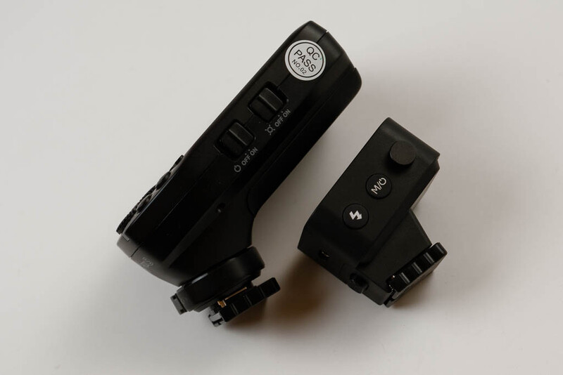 Two black camera flash units mounted on a white surface, positioned at different angles.