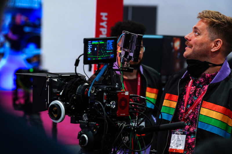 Cinematographer operating a professional cinema camera with external monitor and color-graded display in a studio setting.