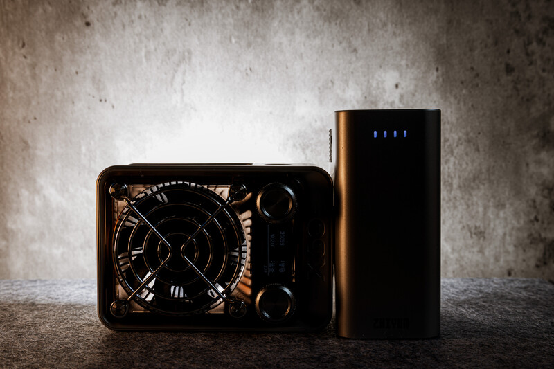 Two portable power banks displayed against a textured concrete wall and surface.